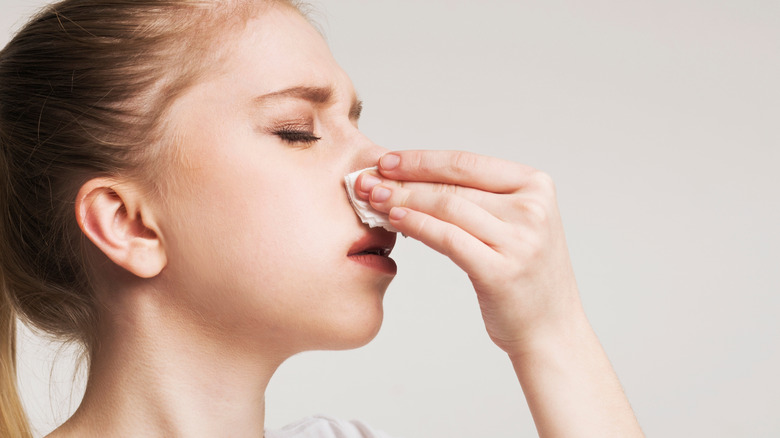 Woman holding a tissue up to her nostrils