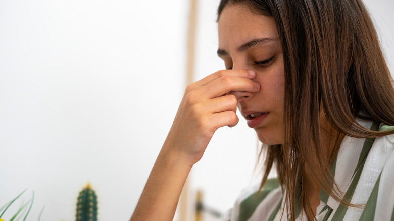Woman with head in neutral position, pinching her nose
