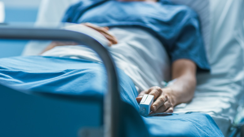 Person in hospital bed with pulse oximeter on finger