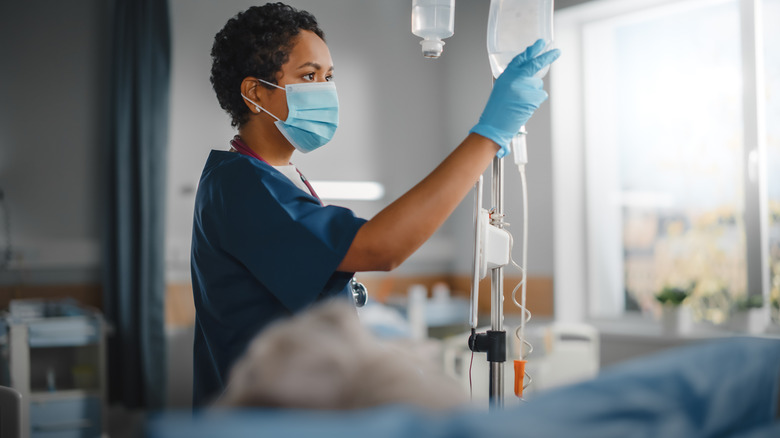 Nurse checking a patients' IV fluids in a hospital room