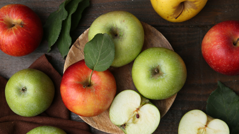 Different ripe apples on wooden table