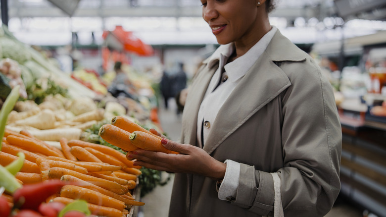 Woman selecting orange carrots at supermarket