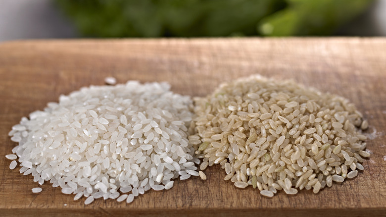 Uncooked white and brown rice side by side on table