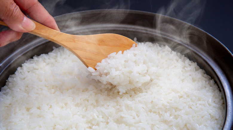 Hand stirring white rice in pot