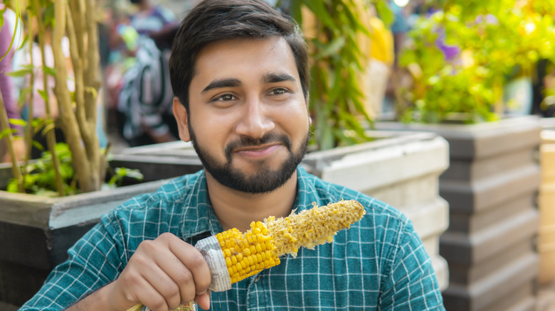 Man eating cooked yellow corn on the cob