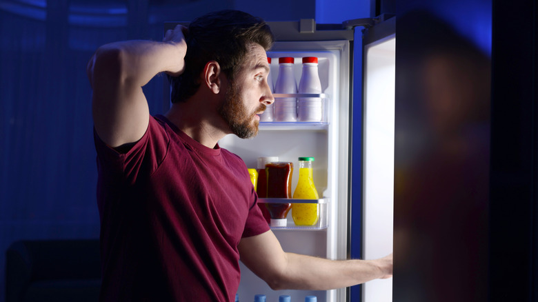 Man looking inside fridge at night