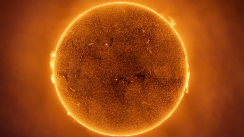 The sun is seen glowing orange with surface details visible