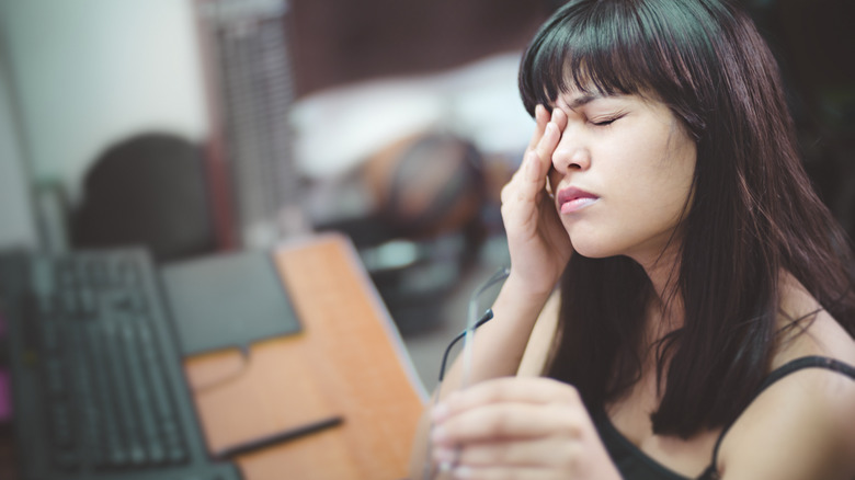 Woman touching eyes, feeling strain from close up work