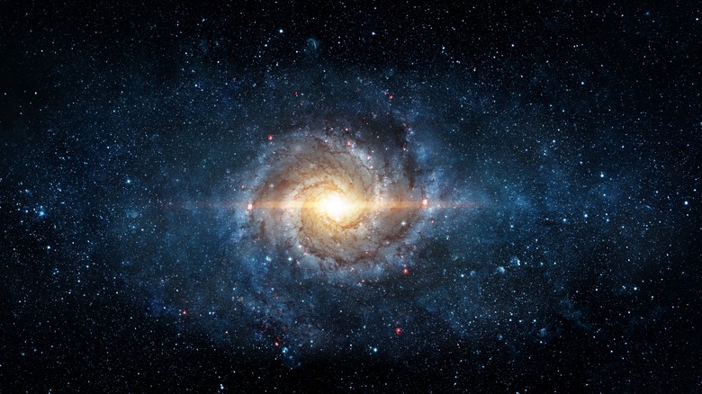 A galaxy is seen in a dark sky surrounded by stars