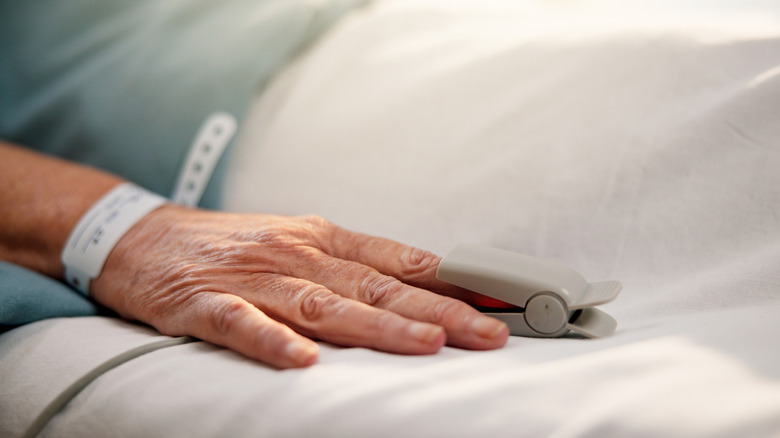 A close up a patient's hand with an oximeter clipped to the finger.