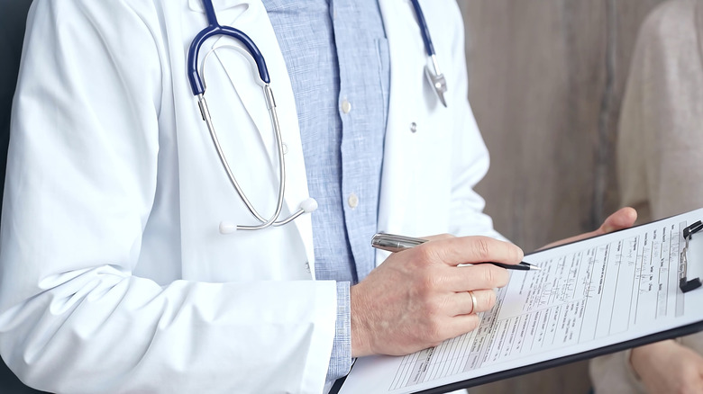 A doctor holding a clipboard and taking notes.