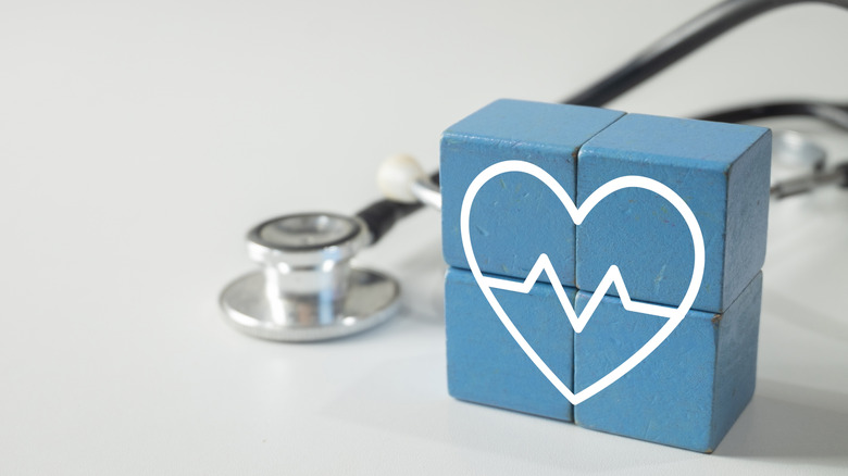 Blocks with a painted heart stacked together with a stethoscope resting in the background.