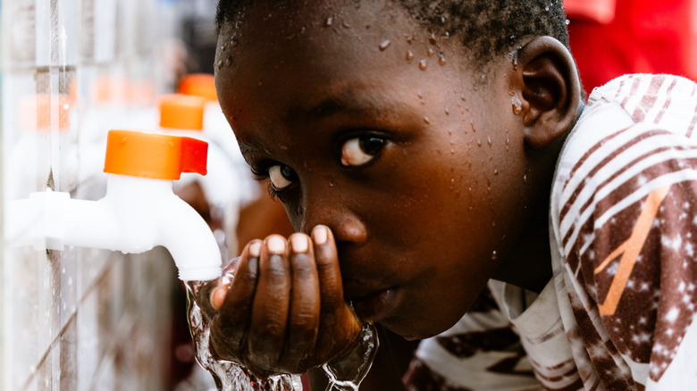 African child drinking clean water from a community well in Tanzania