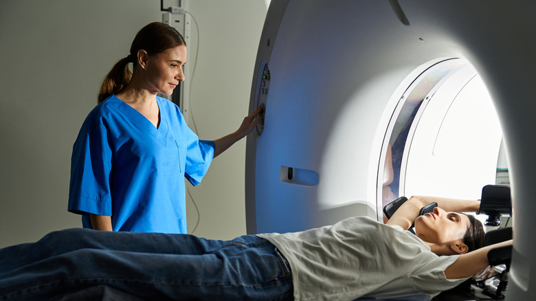 Patient prepares to undergo an MRI scan as a radiology technician operates the scanner