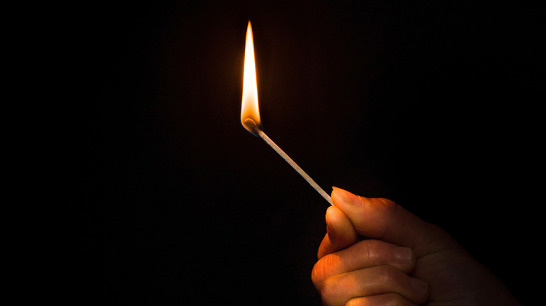 hand holding match in the dark