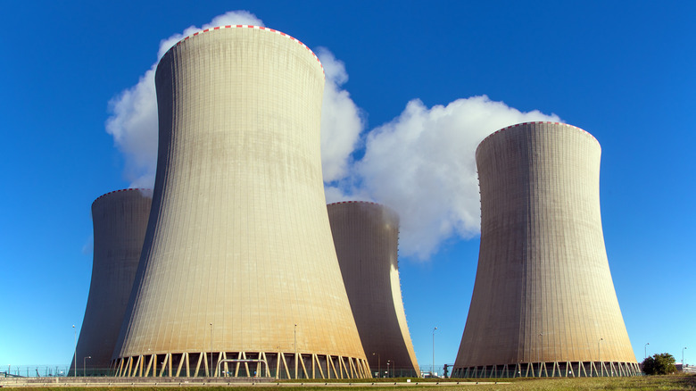 Concrete cooling towers of a power plant billowing white steam into a blue sky