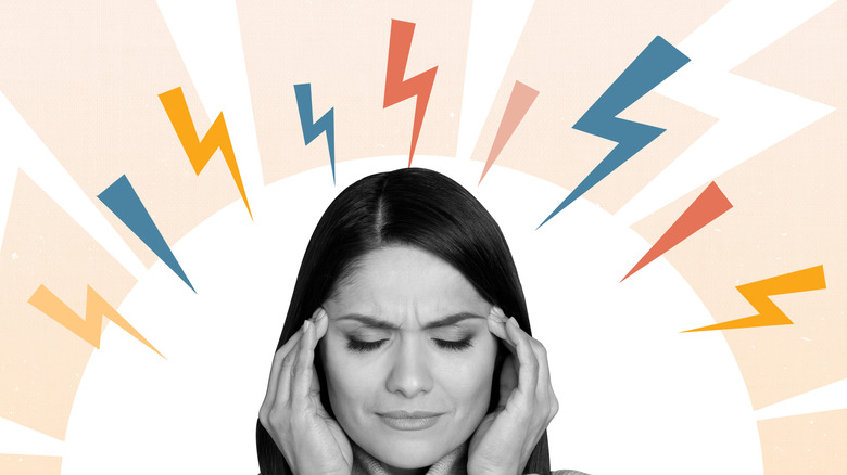 Woman holding her temples with her fingers and colorful lightning bolts surrounding her head