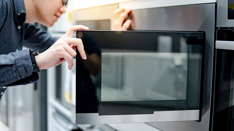 Man looking inside a microwave oven with door open