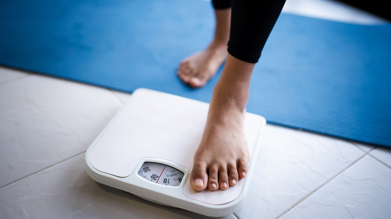 A person setting one foot on a bathroom scale