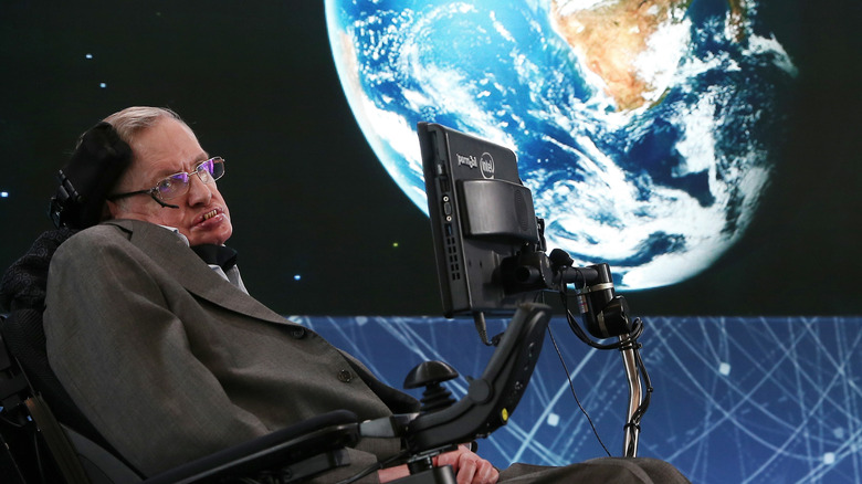 Stephen Hawking lecturing in front of photograph of Earth