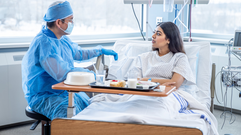 Male doctor speaking with woman in hospital bed