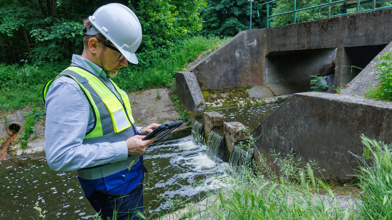 Hydrologist checks water levels near flood control infrastructure