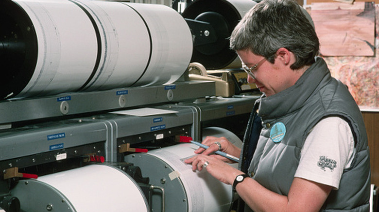 A seismologist checks recorded data on a seismograph