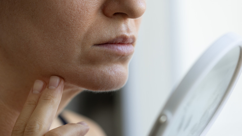 Side view of woman looking at face in mirror