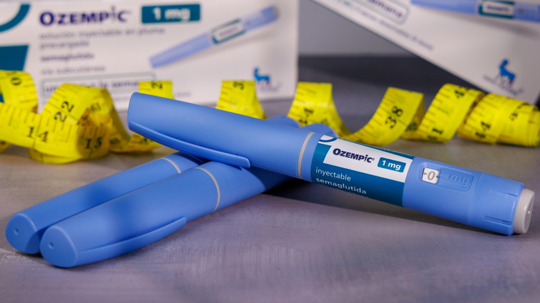 Three Ozempic pens neatly arranged in front of a yellow tailor's tape and product boxes