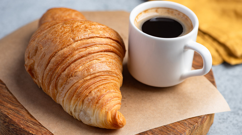 Small white cup of espresso and a croissant