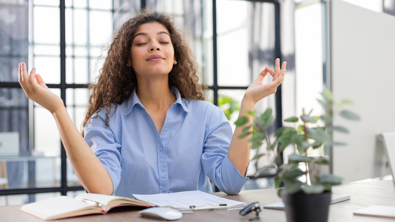 Woman practicing hand mudras to relax at office