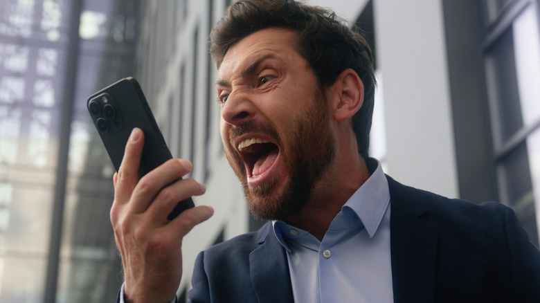 Man yelling while holding a smartphone