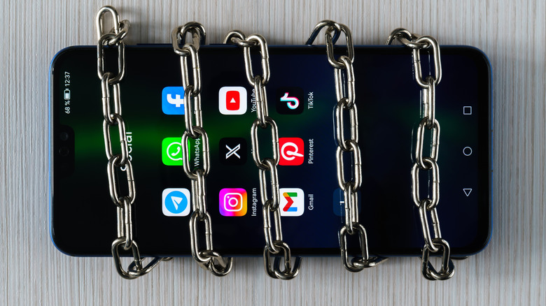 Smartphone with apps on the screen and chain wrapped around it