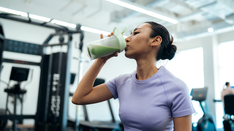 A person drinking a smoothie at the gym.