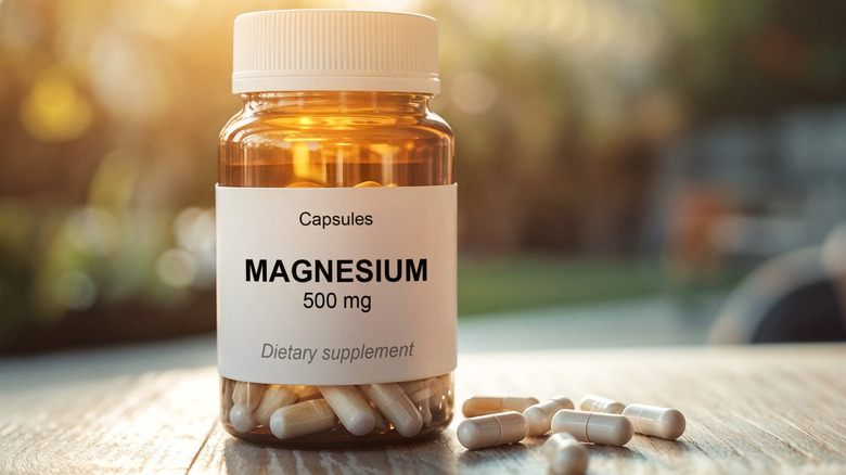 Bottle of magnesium and capsules on a table with the outdoors blurred in the background