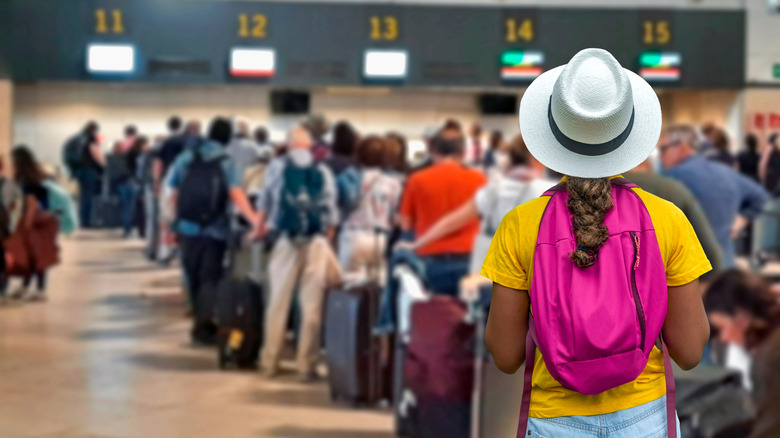 Tourists stand in line to check bags in an airport