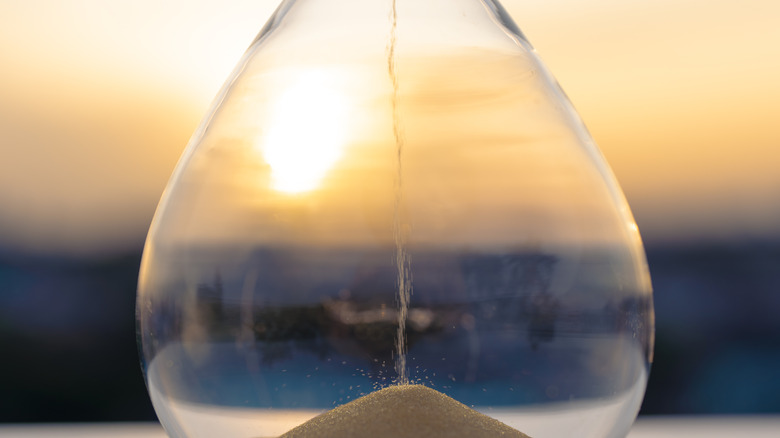 Closeup view of sand trickling through an hourglass