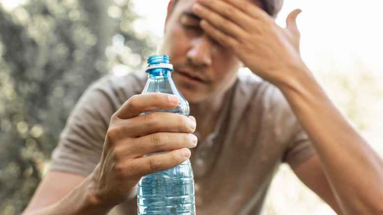 A man sits holding a bottle of water