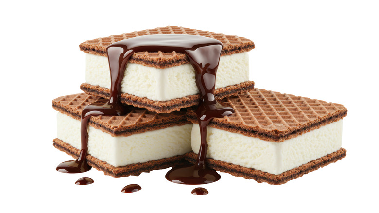 Three ice cream sandwiches stacked on top of each other with melted chocolate syrup on top