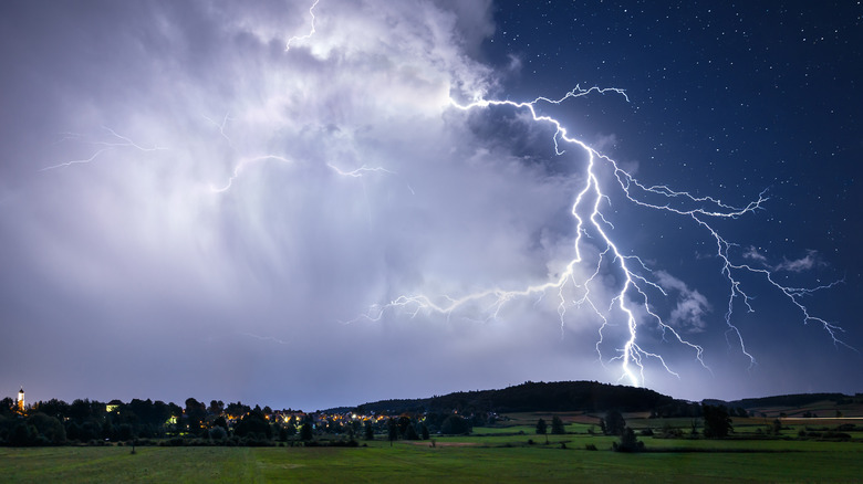 large lightening bolt, multiple forks, over green field, starry sky