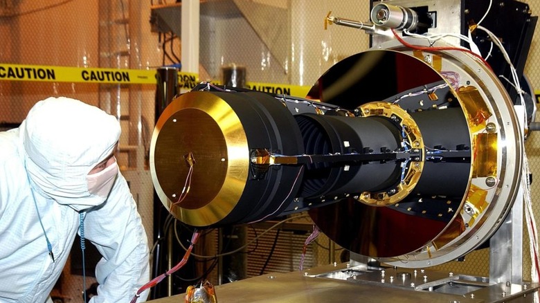 scientist in protective suit inspects golden end of satellite