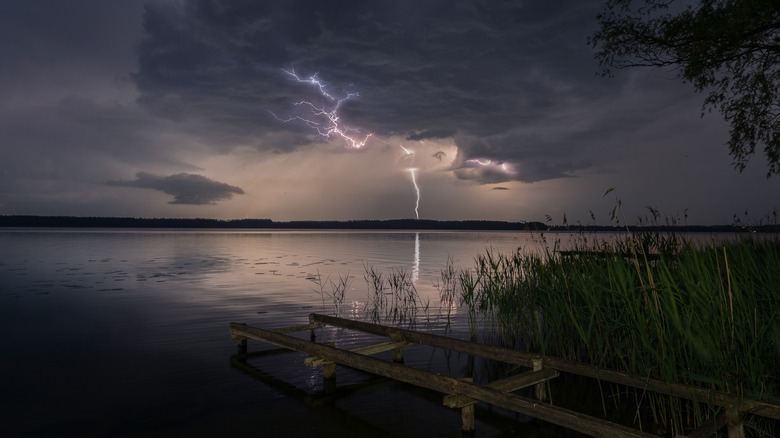 Lightning bolts striking over a calm lake