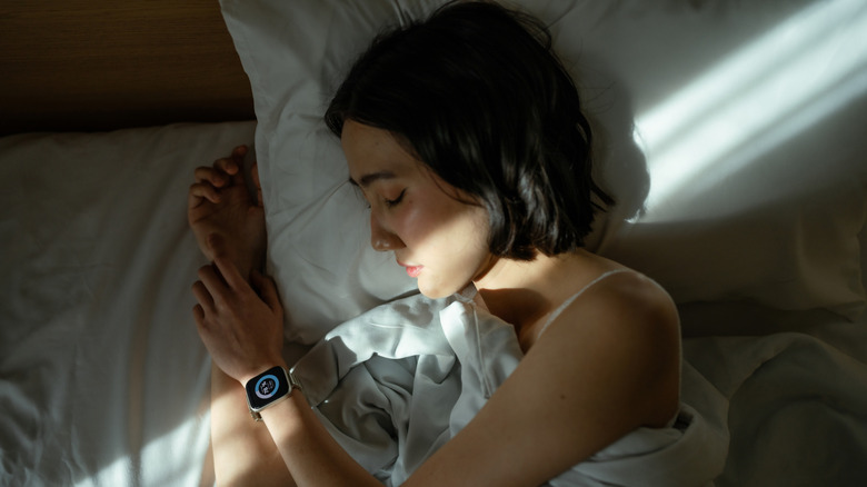 Woman sleeping in bed while wearing a smart watch