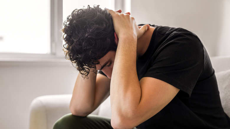 Man sitting in sofa with head down in distress