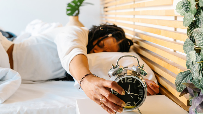 Woman turning off alarm clock while in bed