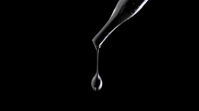Liquid dripping out of pipette on black background