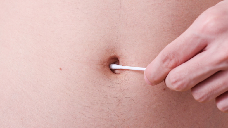 Person using a cotton swab to clean belly button