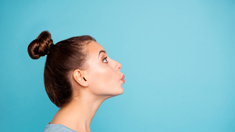 Profile view of young woman whistling