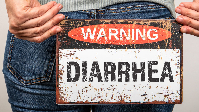 Rear view of a woman holding a "Warning Diarrhea" sign in front of her buttocks