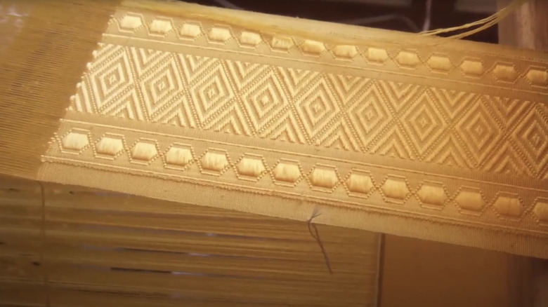 A cape made of golden orb weaver spider silk is seen in closeup